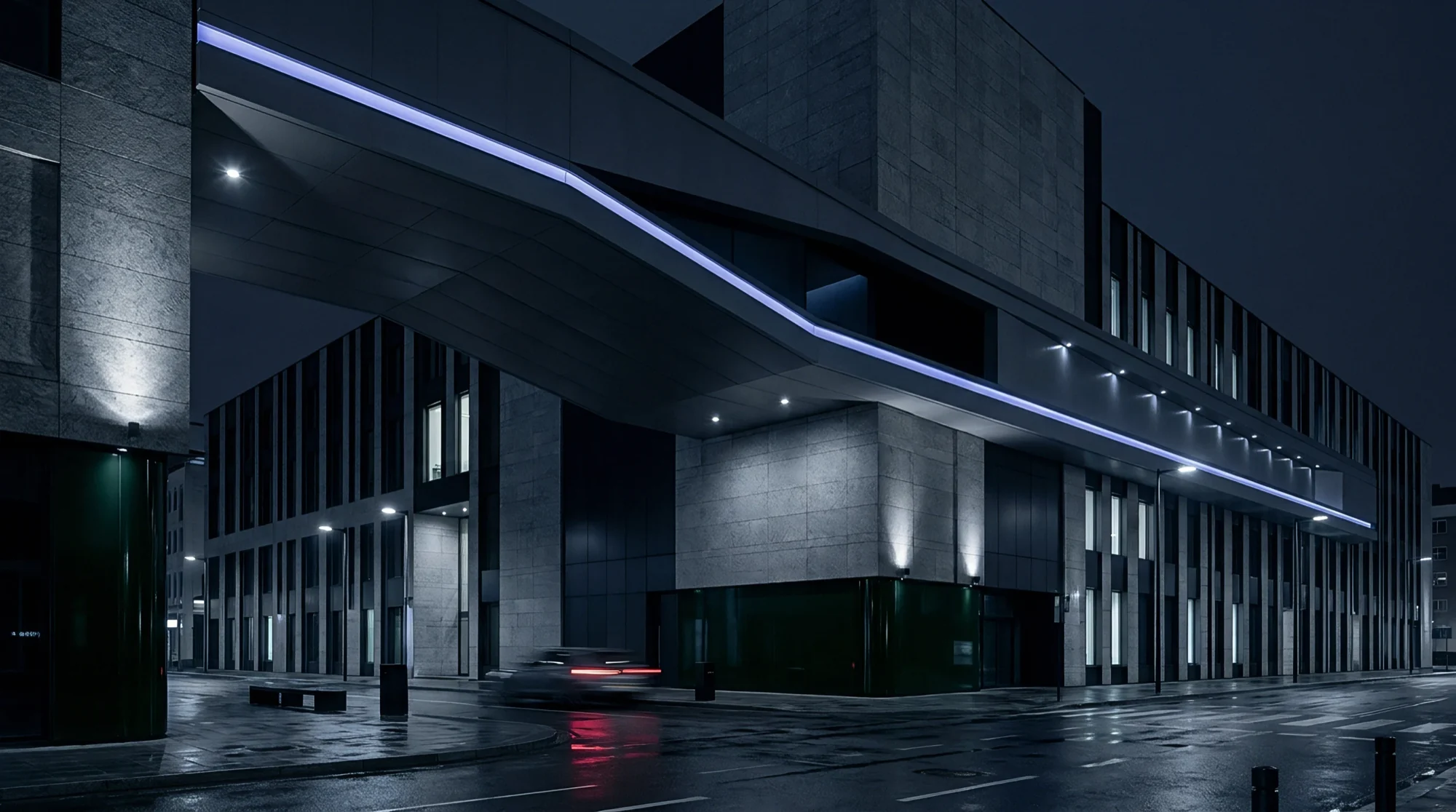 A contemporary building facade with metal cladding and architectural accent lighting, seen at night.
