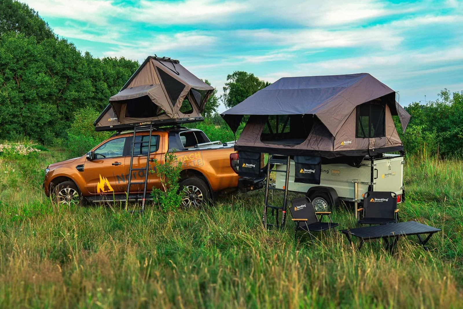 An orange pickup with a rooftop tent and a matching trailer with a second tent, parked in a green meadow: the vehicle before the UPNORTH livery.