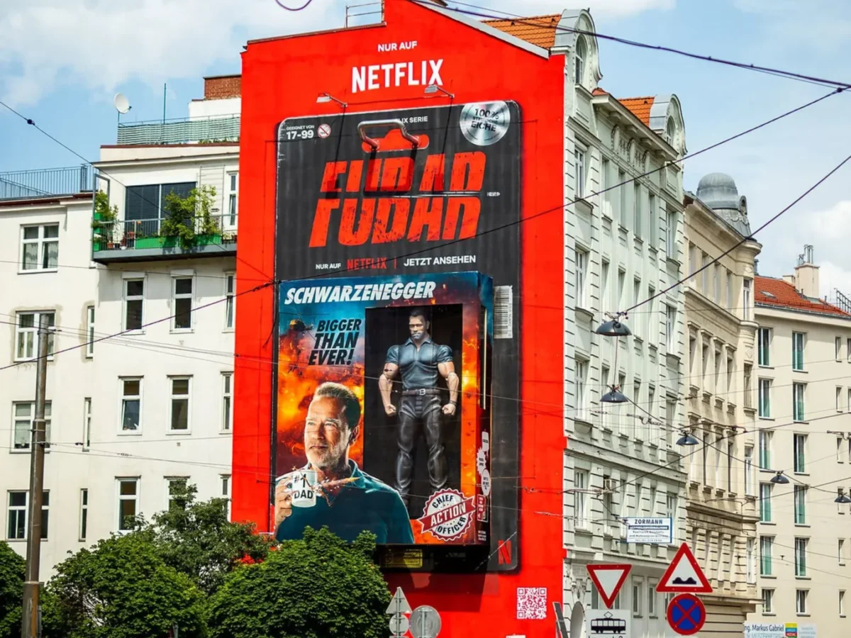 A hand-painted advertising mural for a streaming series covers the gable wall of a corner building above a tram junction.