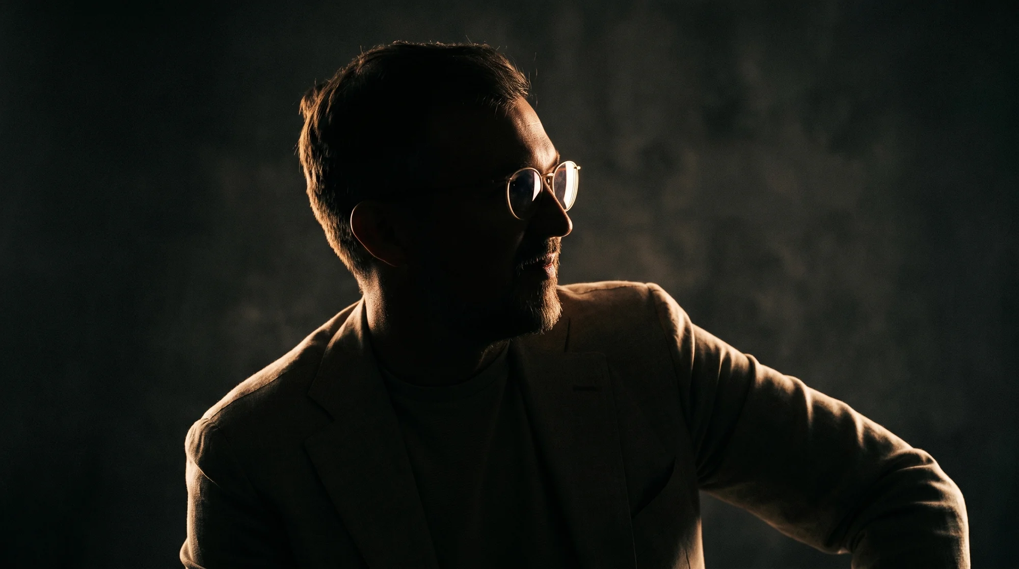 Pierre Blanquett, founder of sentiention, half-lit in profile against a dark studio ground.